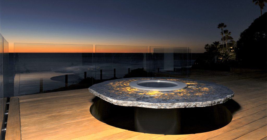 A round bbq grill plate built in to a marble stone on a waterfront verandah.