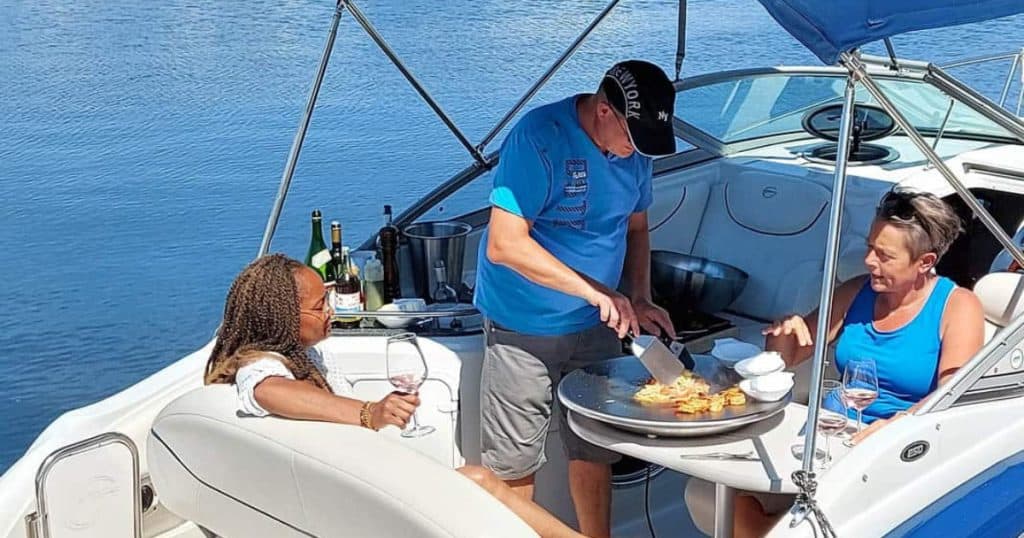 A yacht with people cooking on a bbq grill.
