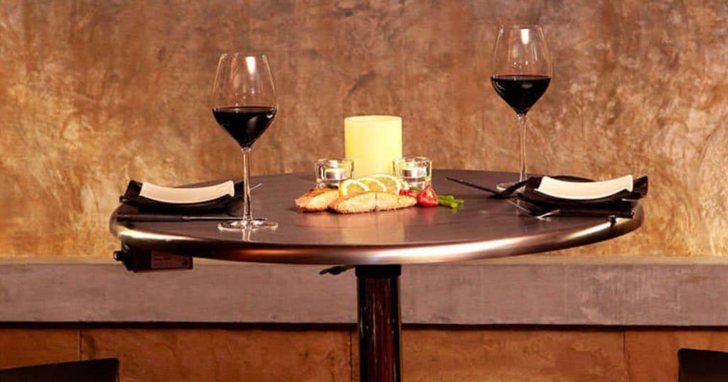 A round bbq grill table which is set for a romantic dinner